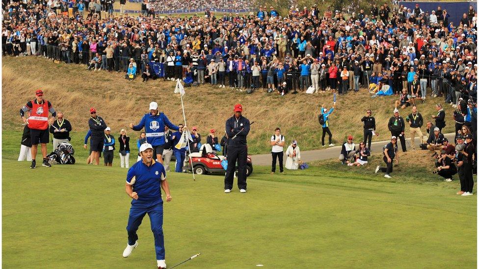 Jon Rahm pots ball in front of crowd.