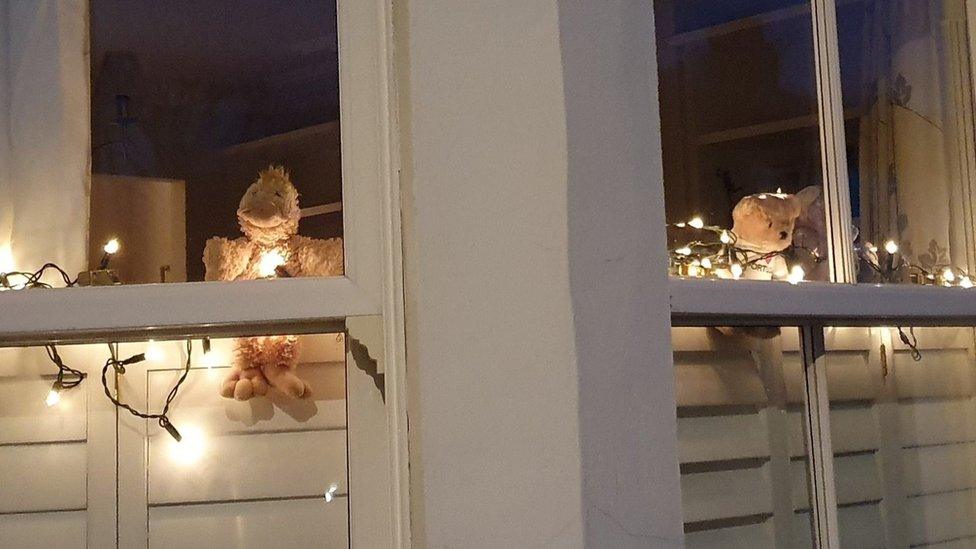 Teddy bears lit up in a window in London