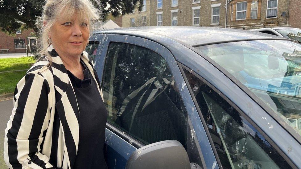 Mary Bates beside car covered in Starling guano