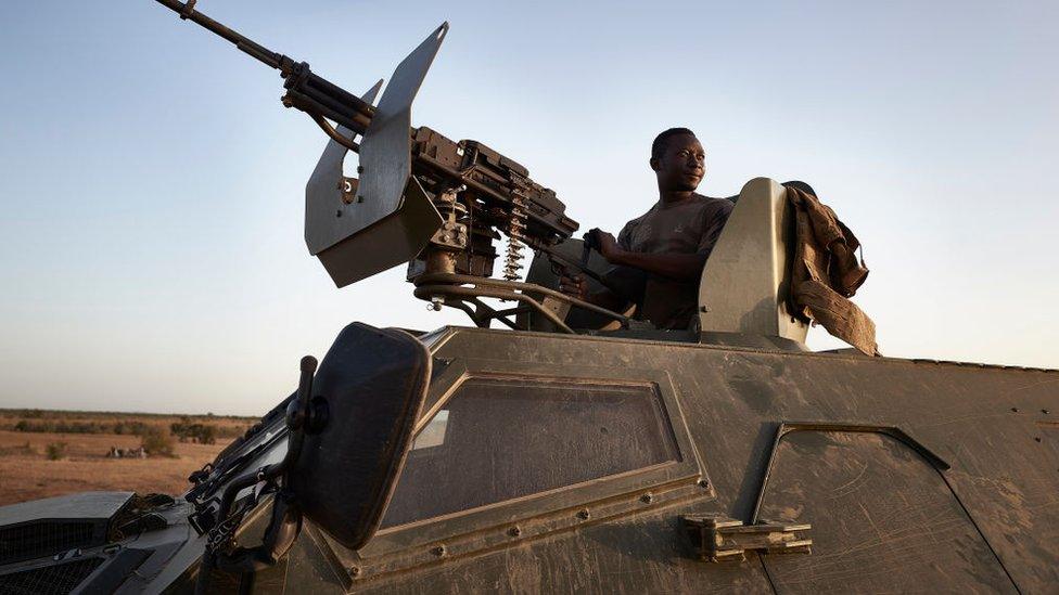 A soldier of the Burkina Faso Army poses on the top of an armoured vehicle during a patrol in the Soum region in northern Burkina Faso on November 12, 2019.