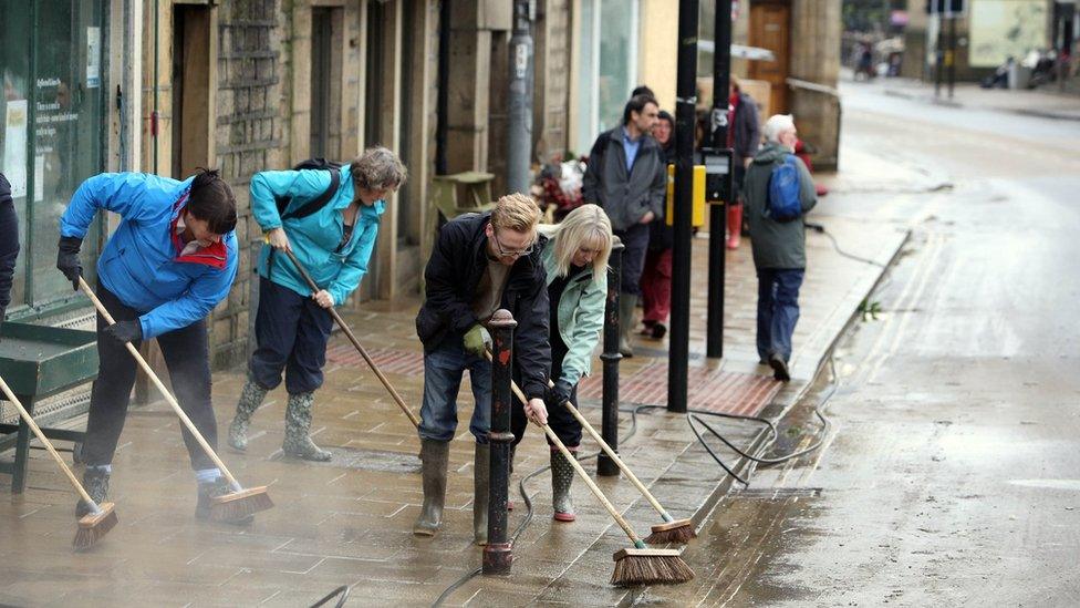 People sweeping water away