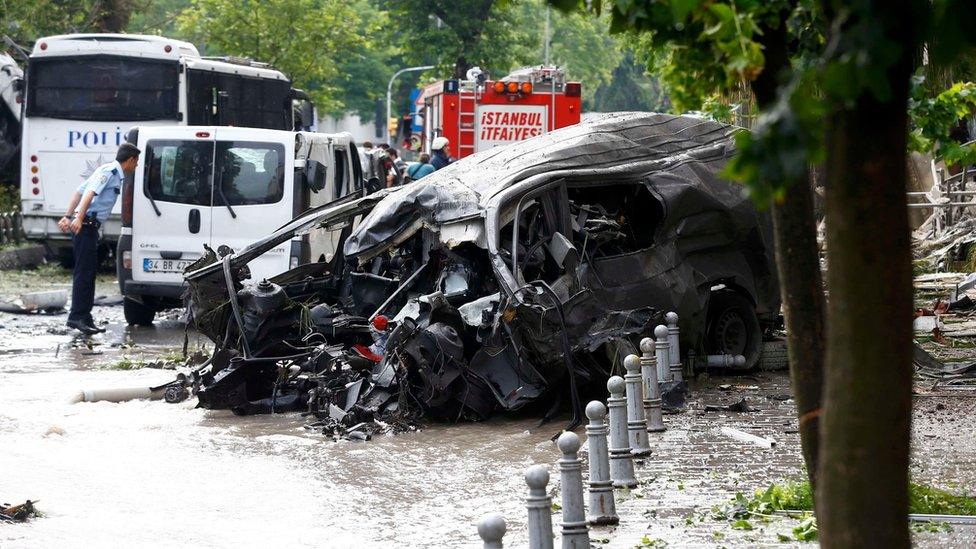 A destroyed van is pictured near a Turkish police bus which was targeted in a bomb attack in a central Istanbul district