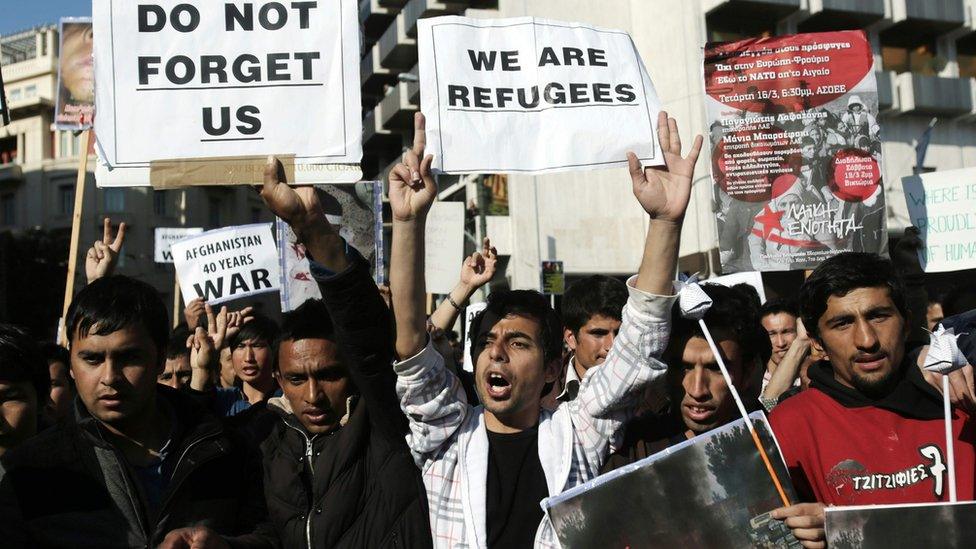 Men shout slogans as they hold banners reading "we are refugees" or " do not forget us"