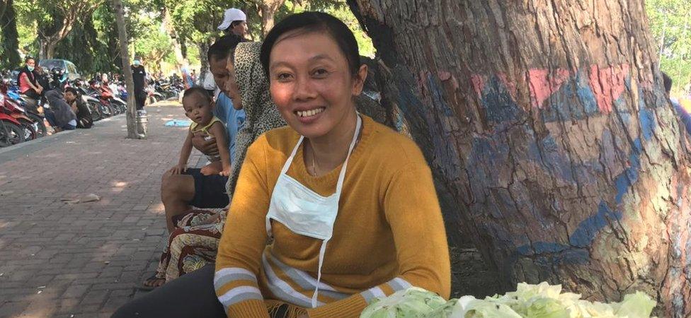 Erna Wahyuni smiles in front of a basket of cabbage