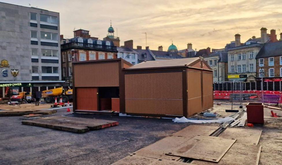 Stalls with wooden sides, being put into place on the market square.