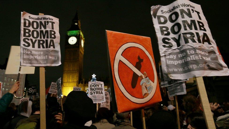 Anti-war protesters hold placards outside the Houses of Parliament as MPs vote for military action in Syria