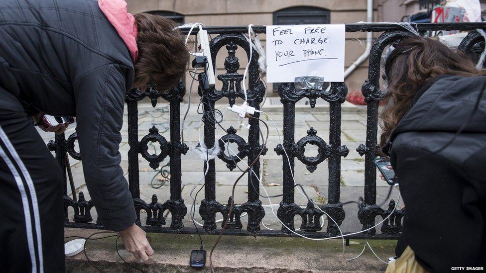 People charge their phones on the street after Hurricane Sandy in New York