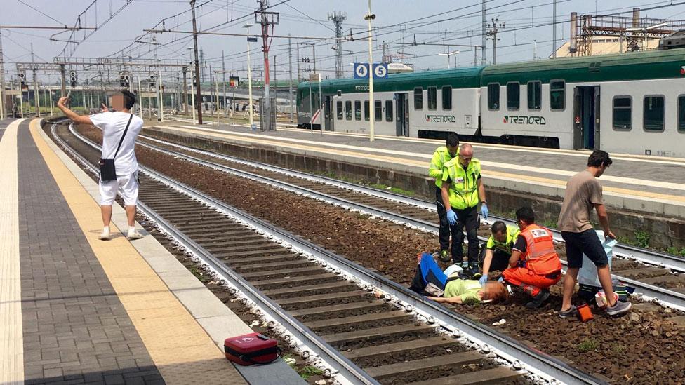 Man takes selfie next to injured person on train tracks