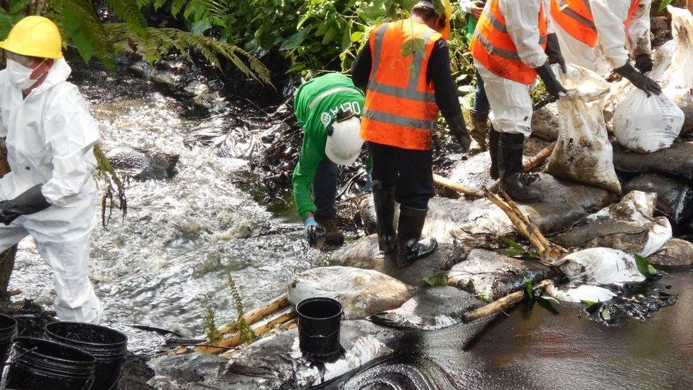 Workers installing barriers to prevent the oil spreading