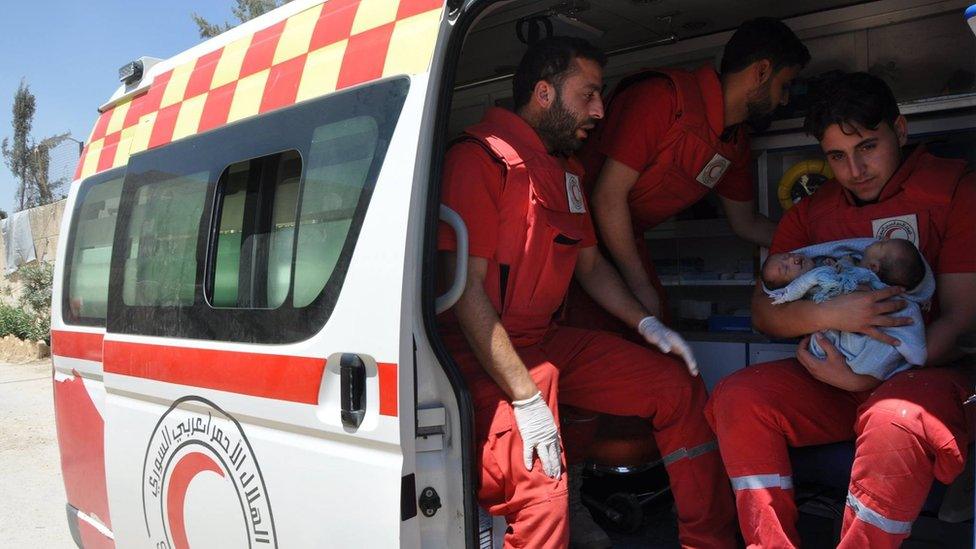 Syrian Arab Red Crescent medics hold conjoined twins Nawras and Moaz before evacuating them from Douma (12 August 2016)