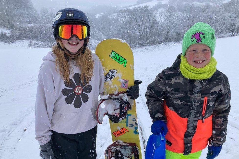 Children playing with a snowboard in the snow