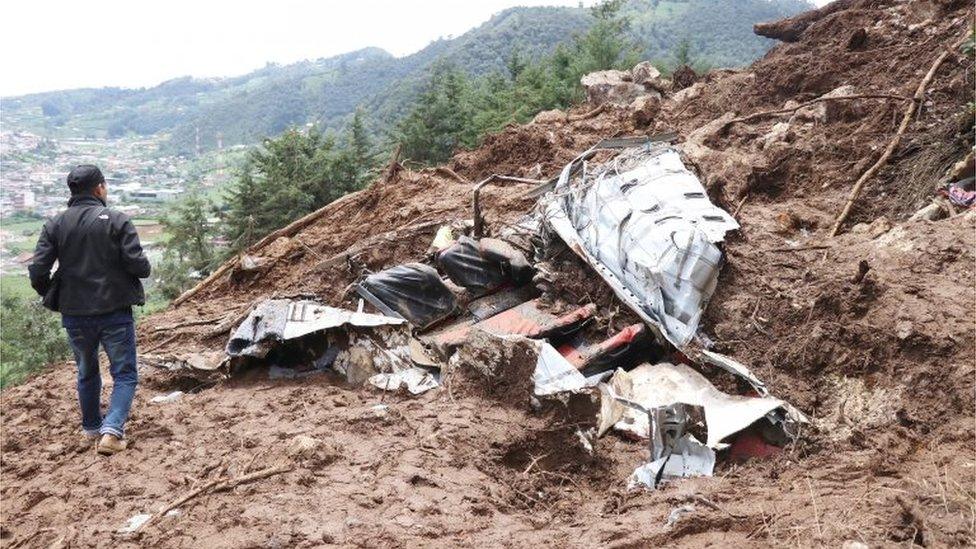 A man walks past the wreckage of a bus at the site of a mudslide in San Pedro Soloma, Guatemala, June 20, 2017.