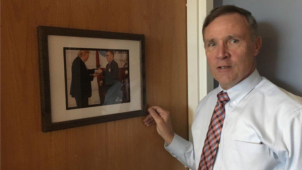 Joe McQuaid next to a photo of himself and Donald Trump