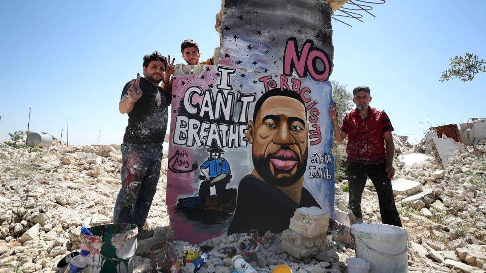 painter Aziz Asmar and his two friends standing by a mural of George Floyd