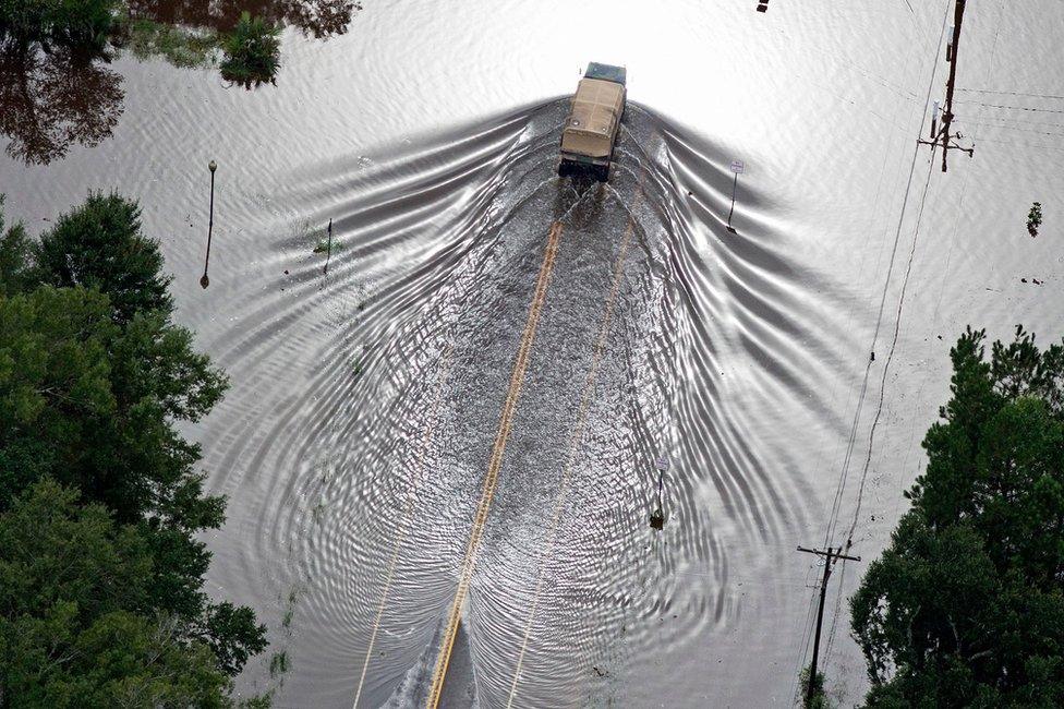 In this aerial photo over Robert, La., Army National Guard, vehicles drive on flooded U.S. Route 190 after heavy rains inundated the region, Saturday, Aug. 13, 2016