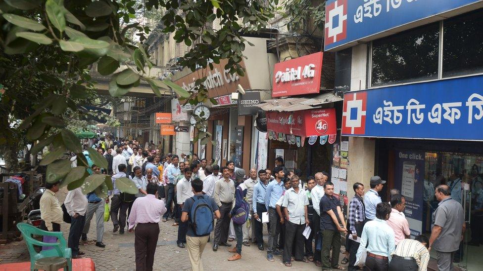 People stand in a queue in front of a private sector bank during a nationwide strike called by major trade unions to protest against demonetisation in Kolkata on November 28, 2016