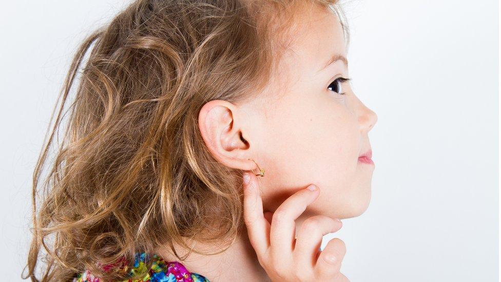 Child with pierced ear showing off her earring