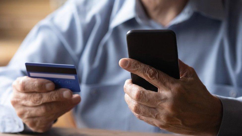 Stock image of man holding credit card and phone