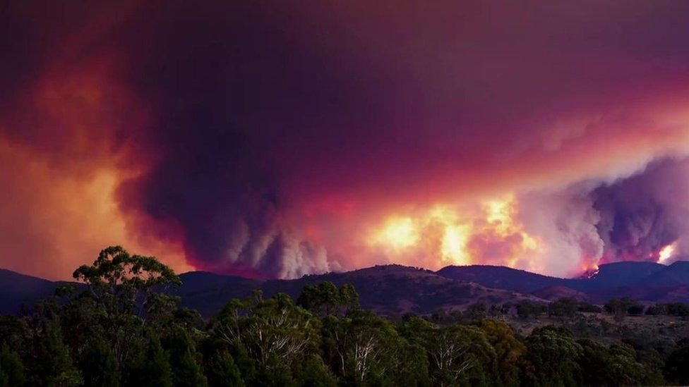 Large fire and smoke over mountains in distance.