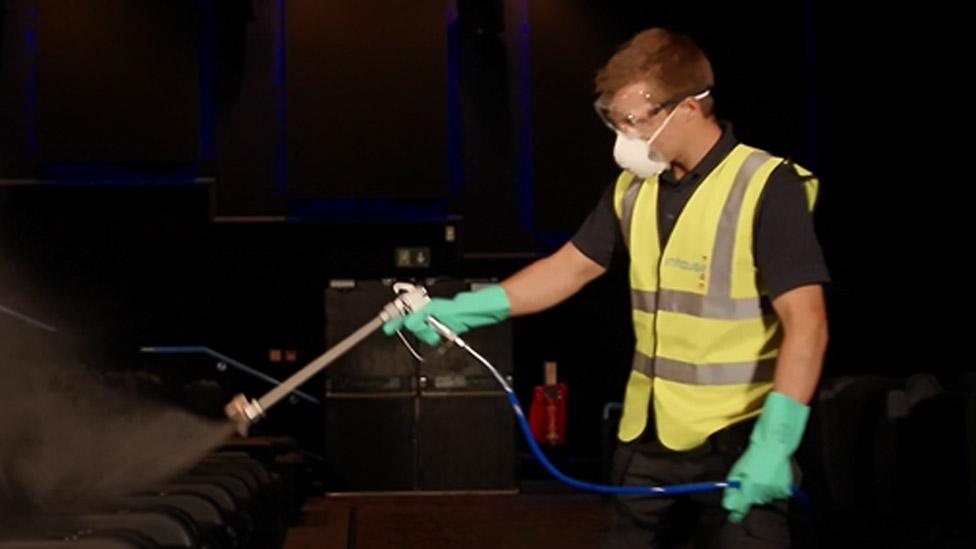 A Showcase employee demonstrating an "anti-viral fogging machine"