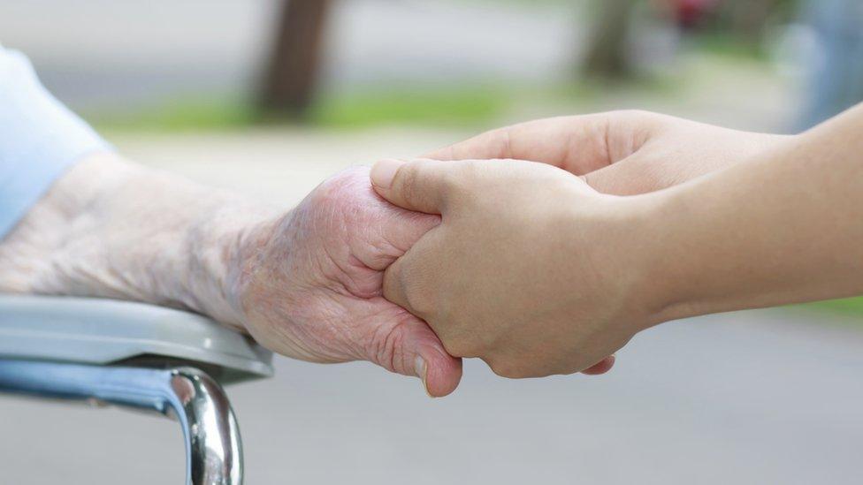 Woman holding elderly woman's hand