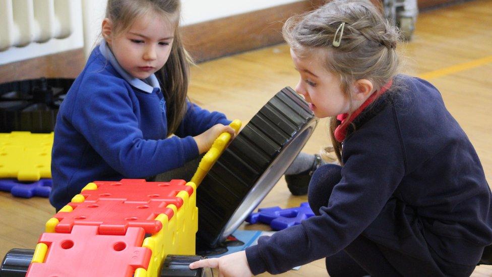 Schoolgirls from both schools building a plastic vehicle