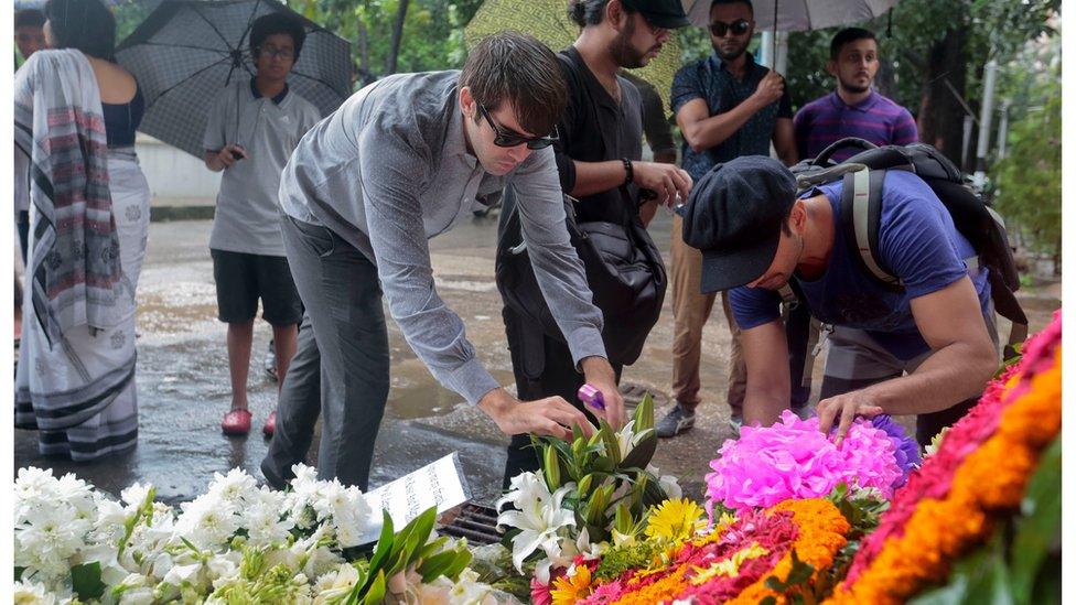 People offer flowers as they pay their respects to the victims of the Holey Artisan Bakery attack