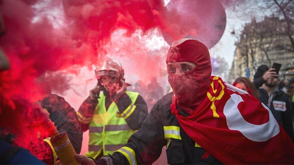 A fireman holds a flare aloft during a protest against pension reform plans in Paris, 10 December 2019