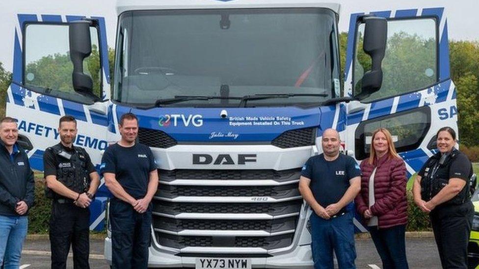 Large blue and white lorry cab with "Julie May" on the front and six people standing in front of it