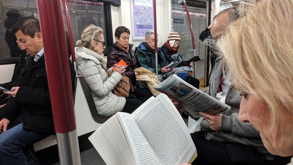 Morning commuters read while riding the TTC Subway in Toronto, Ontario, Canada