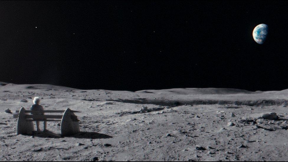 An old man stares at Earth from his bench on the moon