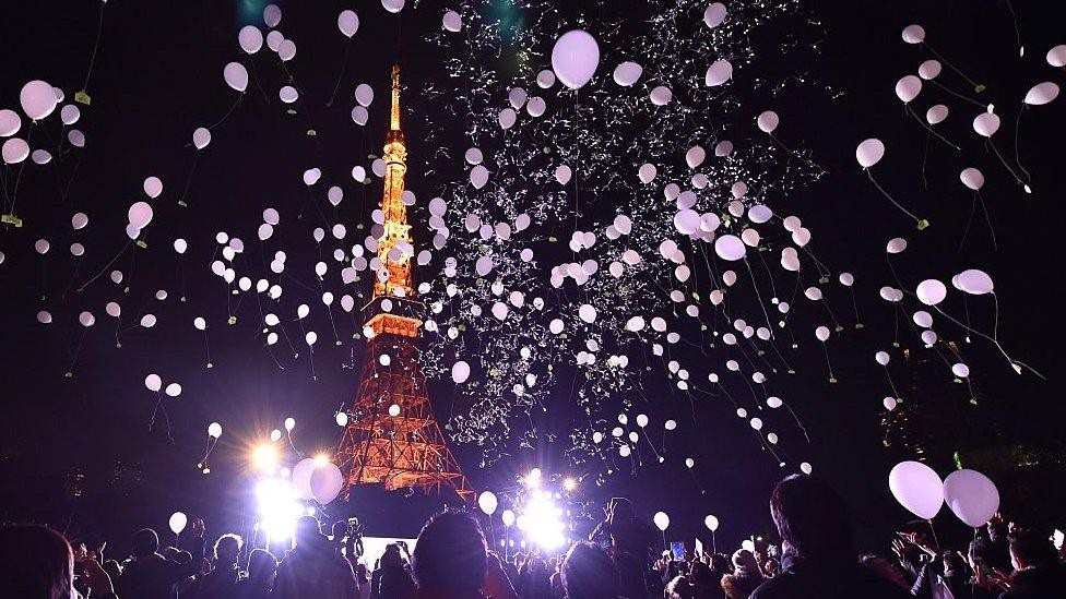 People celebrating New Year at Tokyo Tower on 1 January 2016, showing balloons and the tower lit up.