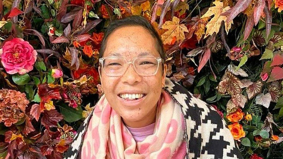 Woman smiling in front of flowers and leaves