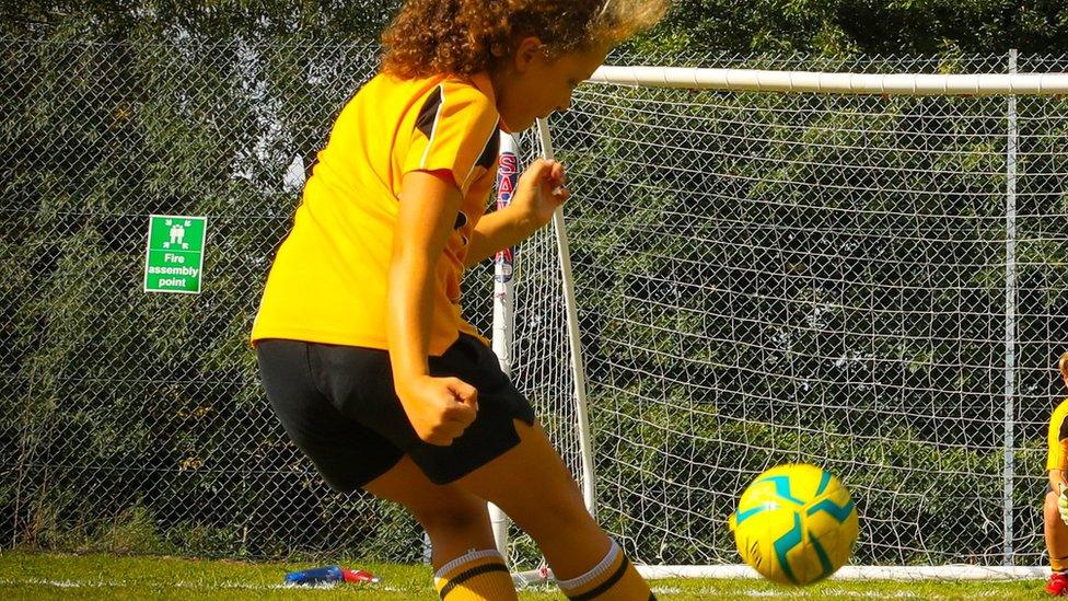 Dora McHardy kicks a football into a goal