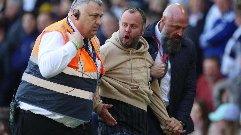 David Derbyshire being led off the pitch by security