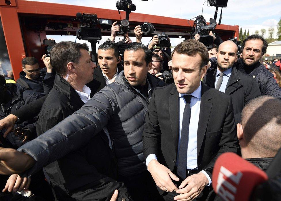 Emmanuel Macron (L) is surrounded by journalists as he talks to Whirlpool employees in front of the company plant in Amiens, France, 26 April