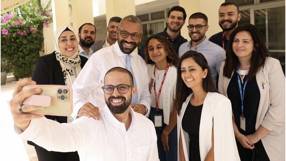 James Cleverly takes a selfie with Chevening graduates in a courtyard