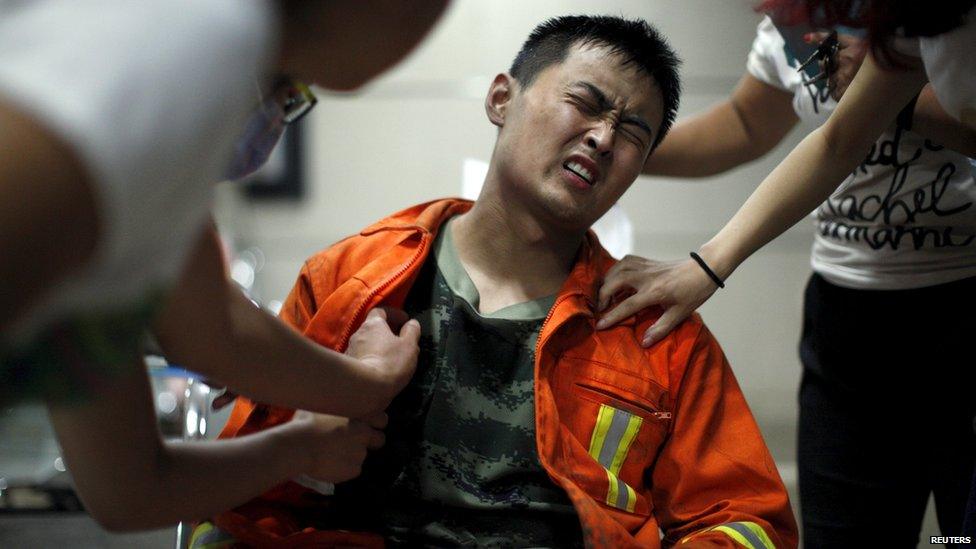 A firefighter reacts as he receives treatment at a hospital after the explosions at the Binhai new district in Tianjin, China, August 13, 2015.