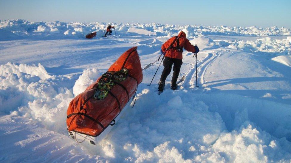 explorer pulling sledge over snow