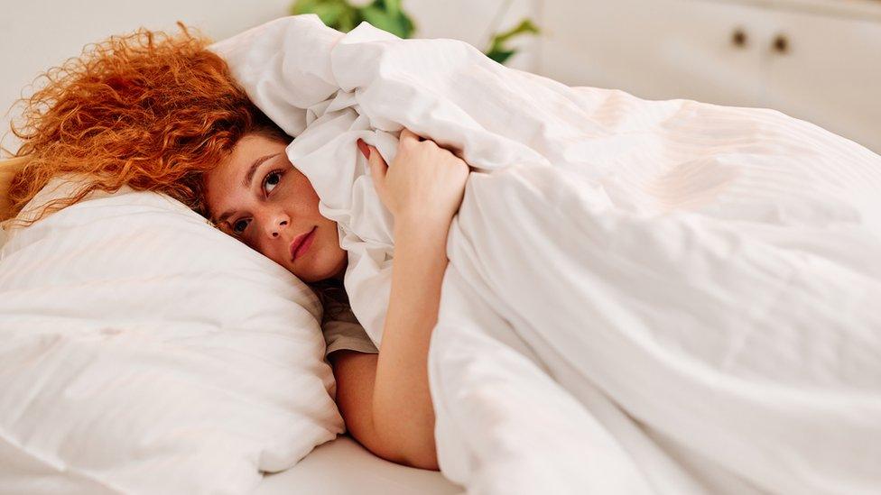 Woman hiding under her duvet