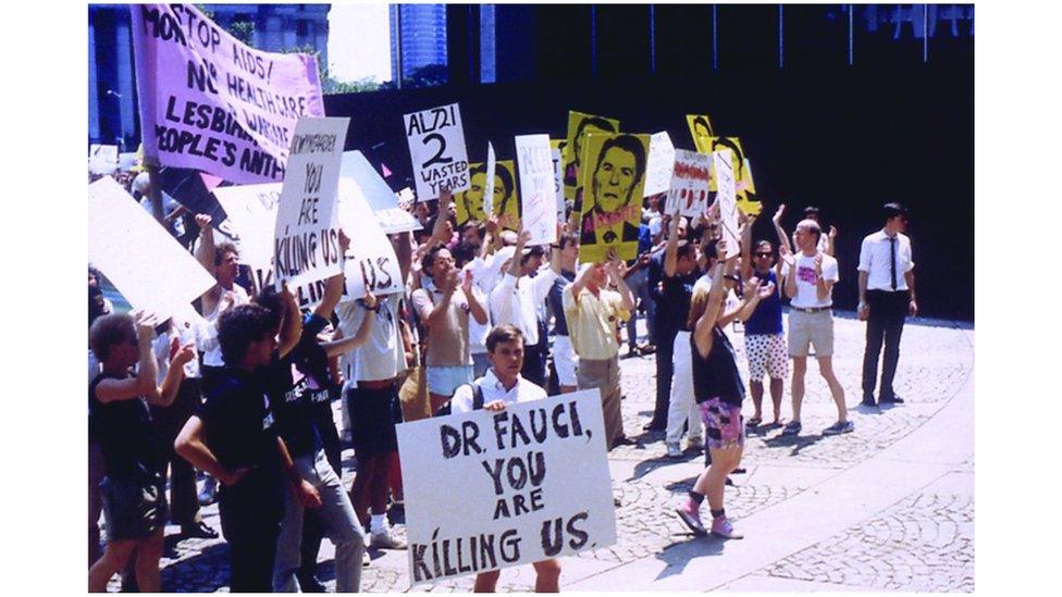 Aids activist holds a sign reading: "Dr Fauci you are killing us"