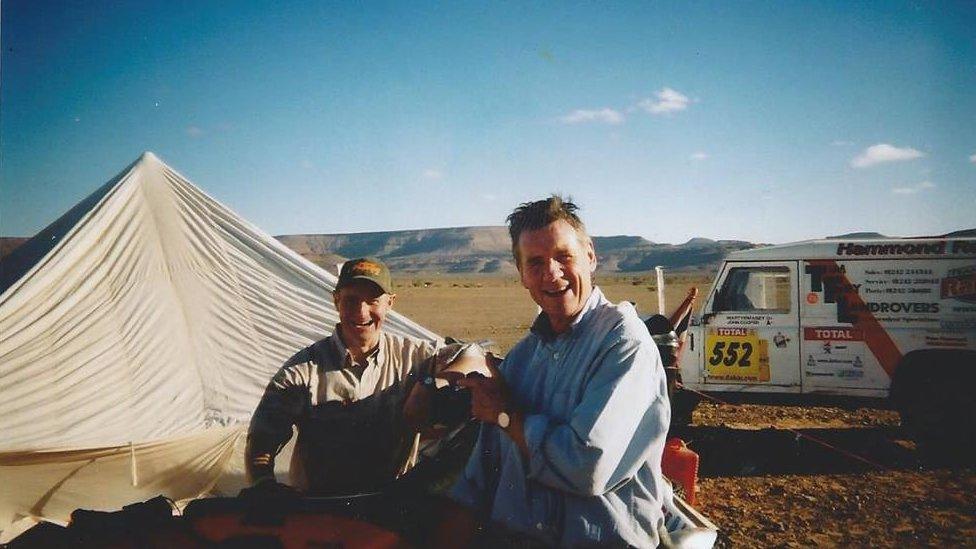 Dave Hammond and Michael Palin standing in front of a tent van branded with 'Hammond'