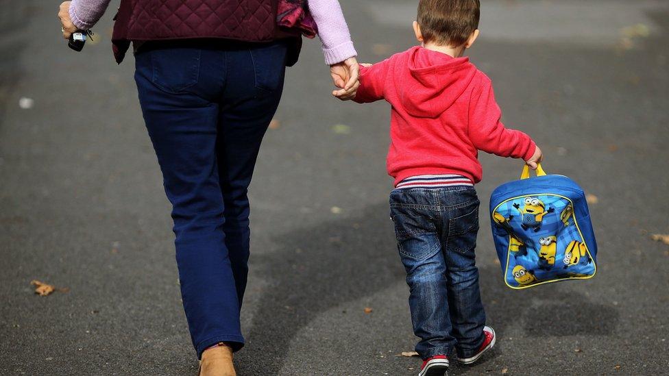 A child being led towards daycare