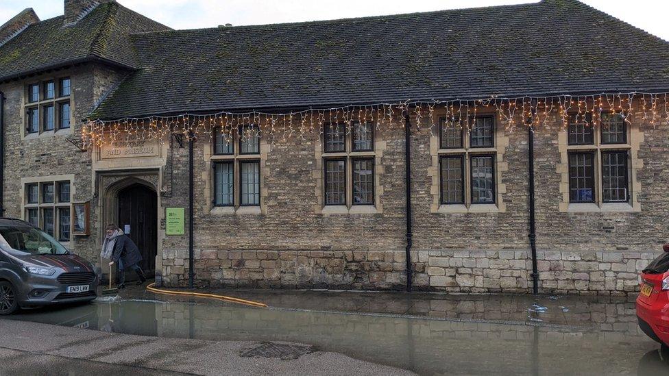 A person sweeps flood water away from a building