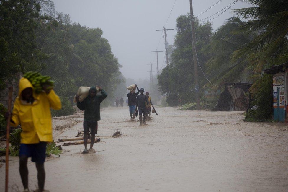 Residents walk in flooded streets as they return to their homes in Leogane, Haiti, on Tuesday, October 4, 2016. Hurricane Matthew slammed into Haitis southwestern tip with howling, 145 mph winds.