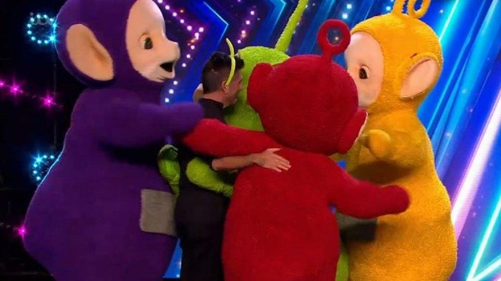 Simon Cowell hugging teletubbies.