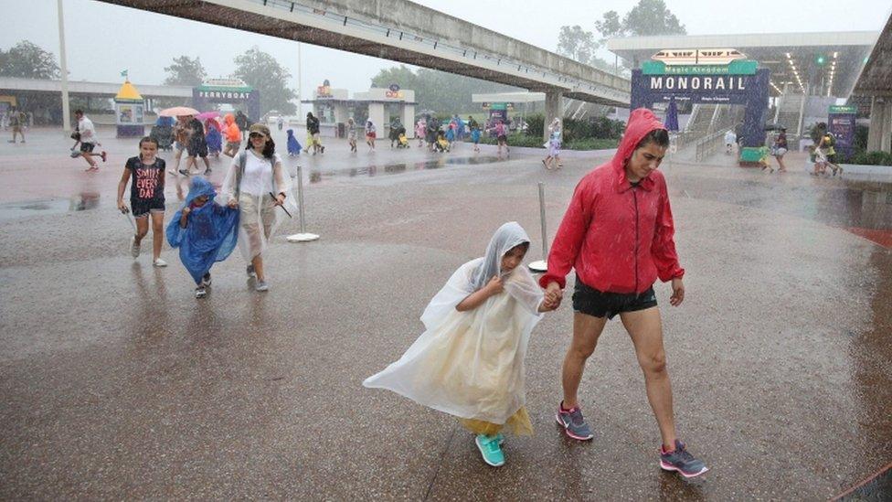 Bedraggled tourists leave Disney's Magfc Kingdom in Orlando as it closes