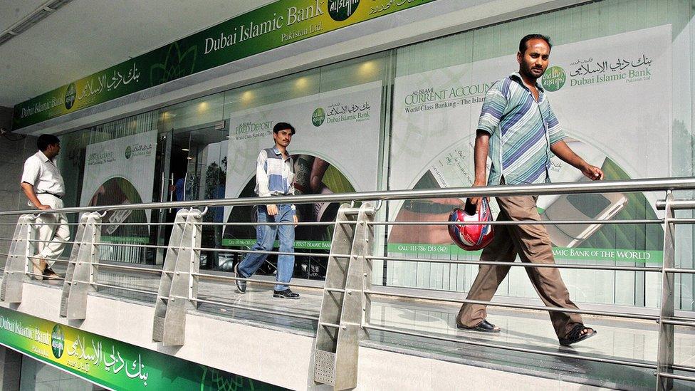 Pakistani men walk by a branch of the Dubai Islamic Bank in Islamabad, 23 May 2006