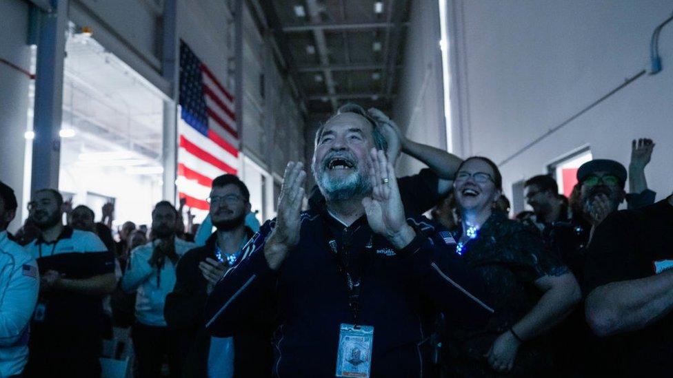 people smiling and cheering at a screen