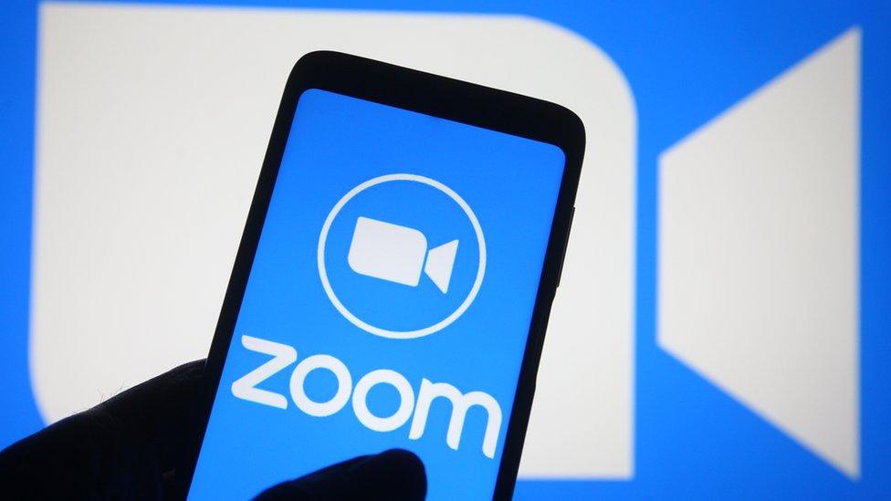 The Zoom video conferencing app is shown on a phone and a screen